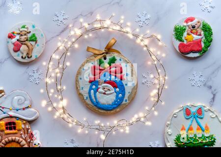 Dekorierter Lebkuchen mit verschiedenen Motiven, Sortiment von leckeren traditionellen Kindergeschenken für Weihnachten. Weihnachten Draufsicht mit festlicher Girlande im Kreis Stockfoto