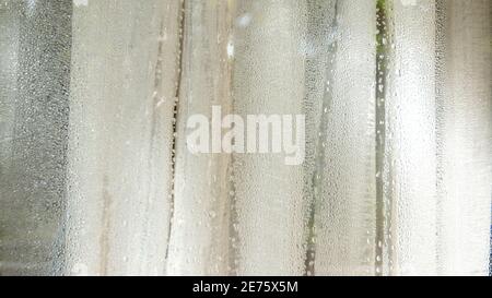 Wassertropfen an der Glastür mit weißen Vorhängen Stockfoto