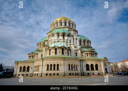 06.01.2021. Sofia. Bulgarien. Prächtige Alexander-Newski-Kathedrale in der Hauptstadt Bulgariens. Bunte Himmel und Parkplatz Autos in der Nähe des Gebäudes. Stockfoto