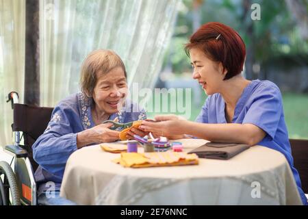 Ältere Frau mit Betreuer in der Nadel Handwerk Ergotherapie für Alzheimer oder Demenz Stockfoto