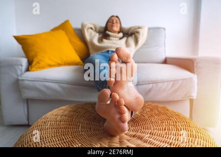 Frau entspannt auf dem Sofa mit geschlossenen Augen und Hände hinter ihrem Kopf Stockfoto
