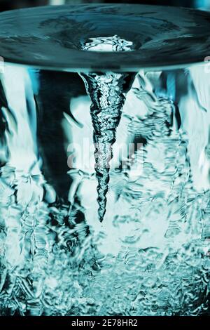 Wasserwirbel in Glasrohr, Tornado, Sturm in blauem Wasserglas mit rotierender Luftsäule, Wasserrohr mit blauem Wirbel Stockfoto