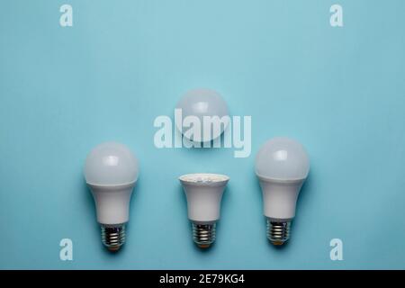 Kreative minimalistische Komposition mit LED-Leuchten auf blauem Hintergrund. Zwei ganze Lampen und eine mit entnommenem Diffusor. Flach liegend Stockfoto