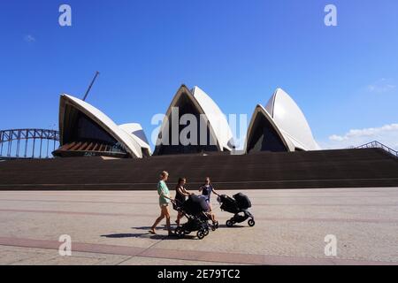 Drei junge Frauen mit Kinderwagen schlendern durch ein verlassene Sydney Vorplatz des Opernhauses, während der internationale Tourismus auf Eis liegt Stockfoto