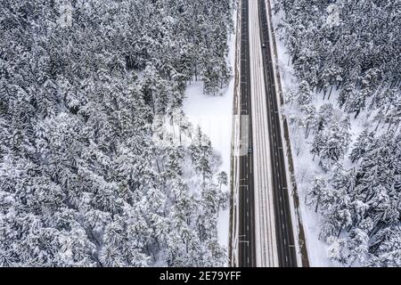 Gerade Straße durch die schönen schneebedeckten Waldlandschaften. Luftbild Stockfoto