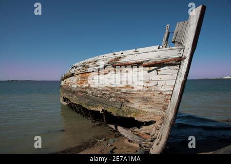 Verrottende Holed Hulk von alten hölzernen Fischerboot auf dem Ufer der Ocean Beach Road Südland Neuseeland befahren. Stockfoto