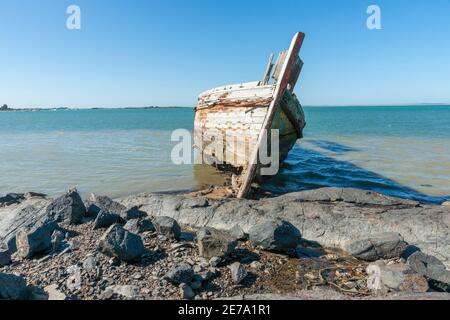 Verrottende Holed Hulk von alten hölzernen Fischerboot auf dem Ufer der Ocean Beach Road Südland Neuseeland befahren. Stockfoto