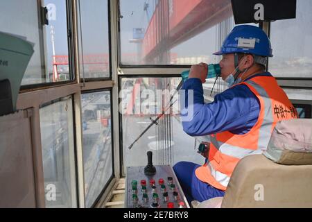 (210130) -- PUTIAN, 30. Januar 2021 (Xinhua) -- Wang Ruifeng trinkt Wasser während einer Arbeitspause im Operationsraum des Trägerkrans auf einem Trägerbaufeld der China Railway 11 Bureau Group Co., Ltd. In der Stadt Putian, südöstlich der Provinz Fujian, 29. Januar 2021. Wang Ruifeng, Jahrgang 1997, arbeitet seit zwei Jahren als Trägerkran-Betreiber. Wang arbeitet hoch über dem Boden und muss mit den Bodenarbeitern zusammenarbeiten, um Kastenträger mit einem Gewicht von über 900 Tonnen genau an den angegebenen Ort zu heben und zu bewegen. Trägerkranbetreiber sind für die Hochgeschwindigkeitsbahn unverzichtbar geworden Stockfoto