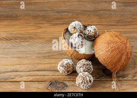 Gesunde Ernährung Konzept. Hausgemachte Kokosnusskugeln in Kokosnussschale auf Holzhintergrund Stockfoto