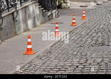 Verkehr Kegel bleiben auf Pflastersteinstraße. Begrenzung des Parkplatzes. Stockfoto