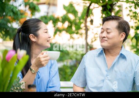 Seniorenpaar mit Essen und Trinken Picknick im Garten Park unterhalten Pflege zusammen, asiatische Rentnerpaar Stockfoto