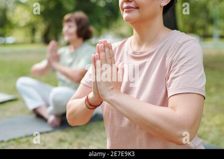 Nahaufnahme einer reifen Frau, die in Lotusstellung sitzt und dabei ist Atemübungen im Freien Stockfoto