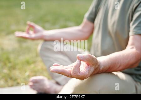 Nahaufnahme eines älteren Mannes, der in Lotusposition sitzt und dabei ist Yoga Stockfoto