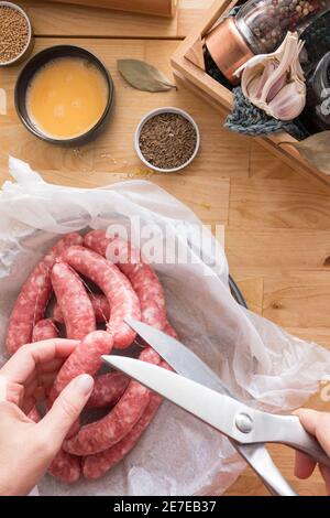 Nahaufnahme einer Frau, die mit einer Schere eine Wurstschnur schneidet. Stockfoto