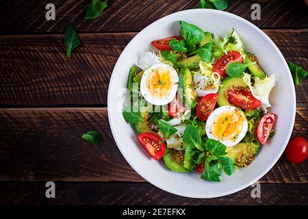 Frischer Avocado-Salat mit Tomaten, Avocado, gekochten Eiern und frischem Salat. Ketogenic Diätfrühstück. Keto, Paleo-Salat. Draufsicht, oben Stockfoto