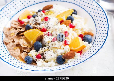 Schüssel mit Flocken mit Quark und Joghurt, Blauberryes und Granatapfel auf weißem Tisch. Fitnessessen. Stockfoto