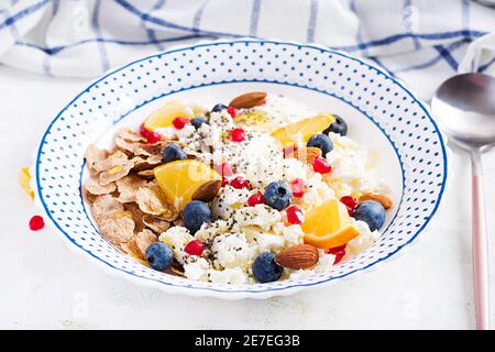 Schüssel mit Flocken mit Quark und Joghurt, Blauberryes und Granatapfel auf weißem Tisch. Fitnessessen. Stockfoto