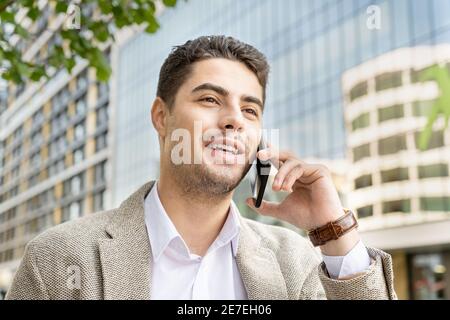 Junger Geschäftsmann im Gespräch auf Handy in der Stadt Stockfoto