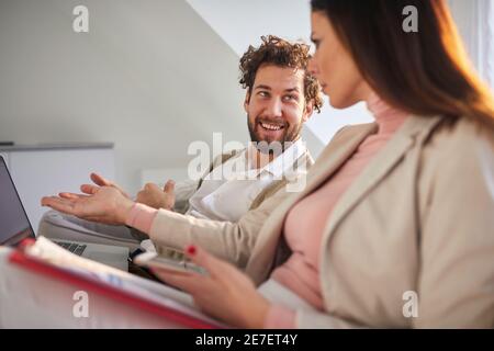Eine junge Geschäftsfrau streitet auf der Couch mit einem gutaussehenden Geschäftsmann in einer entspannten Atmosphäre in einer Wohnung nach einem Arbeitstag. Business, Paar, le Stockfoto