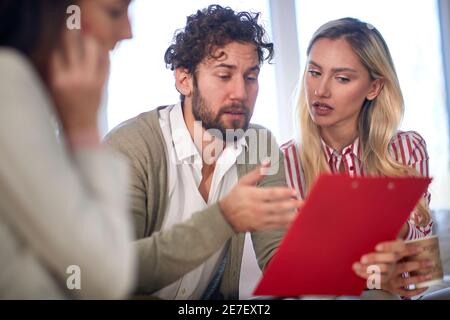 Ein junger Geschäftsmann bei einem Treffen in einer freundlichen Atmosphäre, der seiner Kollegin einige Daten erklärt. Menschen, Unternehmen, Meetings Stockfoto