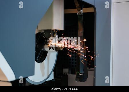 Laserschneidmaschine arbeitet mit zylindrischem Metallwerkstück mit Funken Stockfoto