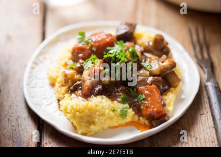 Boeuf Bourguignon mit Karotten, Pilzen, mit Petersilie serviert mit Polenta Stockfoto