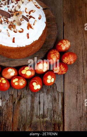 Osterkuchen und bunte Eier. Rustikales Essen auf einem Holztisch. Traditionelles Ei mit Zwiebelschale gefärbt. Muster aus Kleeblättern und Dillblättern. Klassisches Essen für Stockfoto