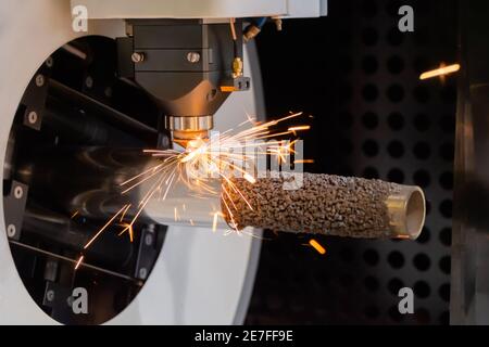 Laserschneidmaschine arbeitet mit zylindrischem Metallwerkstück mit Funken Stockfoto