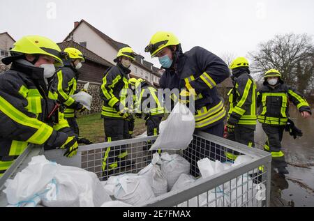 Lindheim, Deutschland. Januar 2021. Feuerwehrleute stapeln Sandsäcke, um Häuser vor der Überschwemmung des Nidder zu schützen. In der Wetterau haben zahlreiche Flüsse ihre Ufer durch den schmelzenden Schnee und die anhaltenden Niederschläge geplatzt. Quelle: Boris Roessler/dpa/Alamy Live News Stockfoto