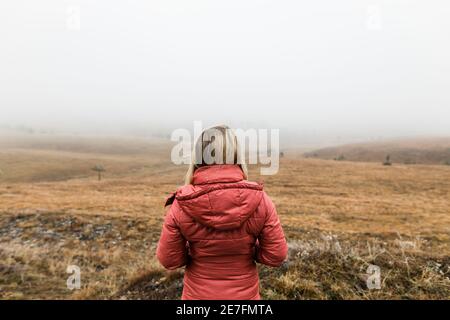 Junge Frau, die die Natur im nebligen Wintermorgen erkundet Stockfoto