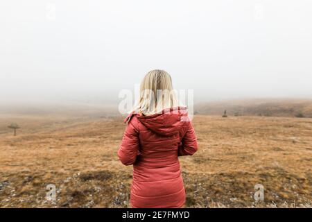 Junge Frau, die die Natur im nebligen Wintermorgen erkundet Stockfoto