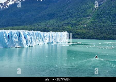 Blaues Eis des Perito Moreno Gletschers im Glaciers Nationalpark in Patagonien, Argentinien mit einem Touristenboot auf dem türkisfarbenen Wasser des Lago Argentino in Th Stockfoto