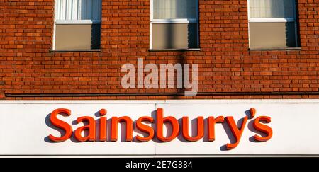 Sainsbury's Logo und Schild über Supermarkt Eingang in Golders Green. Orangefarbene Buchstaben auf weißem Hintergrund. Stockfoto