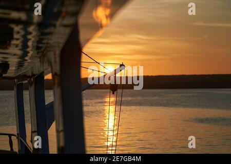 Schöner und spektakulärer Sonnenuntergang über einer Motoryacht mit Reflexen auf der weißen Farbe und Details des Schiffes, in der graet darwin Bucht von ge liegen Stockfoto