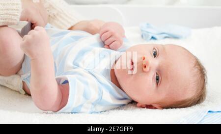 Mutter kleiden ihren kleinen Sohn liegend auf Wickeltisch zu Hause. Konzept von Babys und Neugeborenen Hygiene und Gesundheitsversorgung. Fürsorgliche Eltern mit wenig Stockfoto