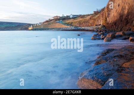 Am frühen Morgen Blick auf Robin Hood's Bay, zeigt Meer-abgenutzte Klippenaufbruch, Felsen Meer Verteidigung und Meeresmauer Verteidigung unterhalb des Dorfes selbst. Stockfoto