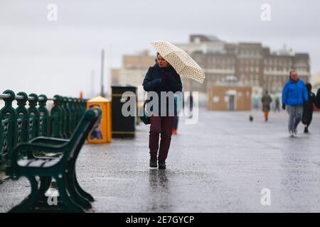 Hove, East Sussex, Großbritannien. Januar 2021, 30. Wetter in Großbritannien: Ein regnerischer Tag an der Strandpromenade, an dem die Menschen zwischen Hove und der Hauptstadt Brighton spazieren gehen und täglich Sport treiben. Eine Frau beschirmt sich mit einem Regenschirm gegen den Regen. Foto-Kredit: Paul Lawrenson/Alamy Live Nachrichten Stockfoto