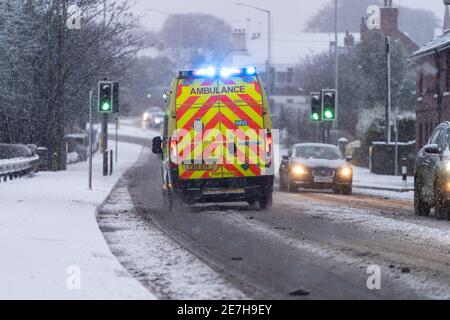 East Midlands Ambulance Service 999 Notfalldienst mit blauen Lichtern Unwetter schwerer Schneefall eisige Straße NHS Sanitäter fahren Schnee Gelbe Warnung Stockfoto