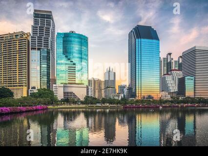 Wolkenkratzer spiegeln sich in einem See bei Dämmerung. Benjakiti Park in Bangkok, Thailand Stockfoto