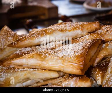 Borek (Blätterteigkuchen mit Käse, der mit Sesamsamen überzogen ist) wird in einem traditionellen orientalischen Restaurant serviert. Ausgewählter Fokus auf die Sesamsamen des Schließens Stockfoto