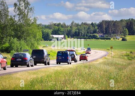 Langsam fahrender Verkehr stand am sonnigen Donnerstag vor Mittsommerabend hinter dem Kleinwagen auf der finnischen zweispurigen Main Road 52 an. Salo, Finnland. Juni 18, 2020 Stockfoto