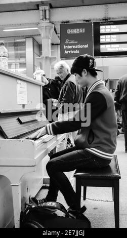 LONDON, ENGLAND, Großbritannien - 2. MAI 2014: Junger Mann spielt Klavier in der Nähe des Eurostar-Ankunftsgates am St. Pancras International Station. Street Pianos Project Stockfoto