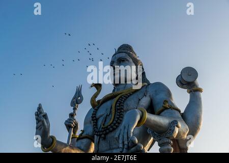 Landschaftsansicht der zweithöchsten Lord Shiva oder Shankara Statue in der Welt mit einem Schwarm für Vögel fliegen. Die Staue liegt an der Küste von Ara Stockfoto