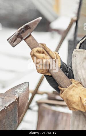 Der Junge, der Sohn des Schmieds, steht am Amboss. Der Prozess des Schmiedens. Stockfoto