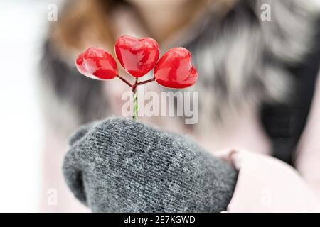 Das Mädchen hält in ihren Händen, die in Fäustlingen sind, einen Strauß roter Herzen. Das Konzept des Valentinstag. Stockfoto