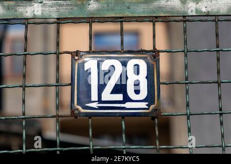 Nummer 128, die Anzahl der Häuser, Wohnungen, Straßen. Die weiße Zahl auf der blauen Metallplatte, die Hausnummer einhundertachtundzwanzigundzwanzig (128) auf dem Ro Stockfoto