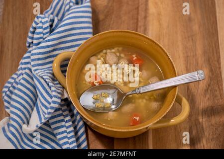 Ein Löffel Hühnchen Nudel Alphabet Suppe buchstabiert aus "TRAGEN SIE EINE MASKE". Stockfoto