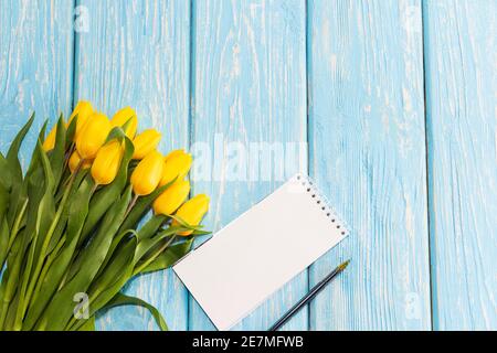 Das Konzept des Muttertages, der achte März, Valentinstag. Tulpen Blume und Notizblock zum Schreiben auf einem hölzernen Hintergrund. Stockfoto