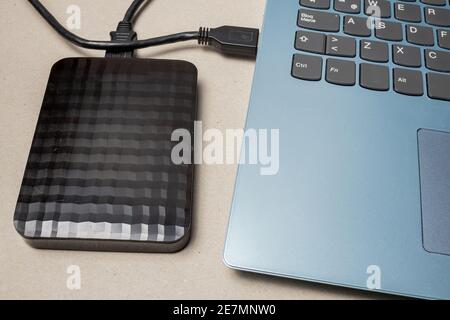 Externe Festplatte mit usb-Kabel an einen Laptop oder Notebook-Computer auf einer rustikalen Oberfläche angeschlossen. Konzepttechnologie Stockfoto