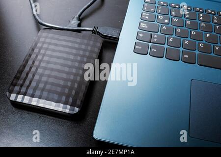 Externe Festplatte mit usb-Kabel an einen Laptop oder Notebook-Computer auf einer schwarzen Oberfläche angeschlossen. Concept-Technologie Stockfoto